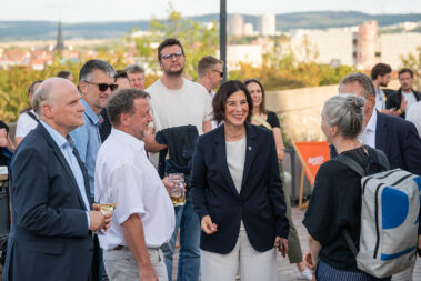 Männer und Frauen stehen im Kreis und unterhalten sich. Darunter ist die Wirtschaftsministerin zu sehen