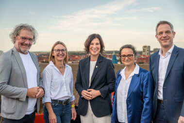Drei Frauen und zwei Männer stehen und lächeln in die Kamera